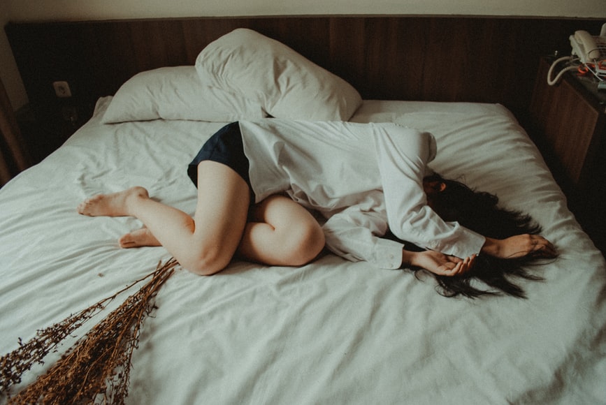 Woman laying on a bed with her face covered 