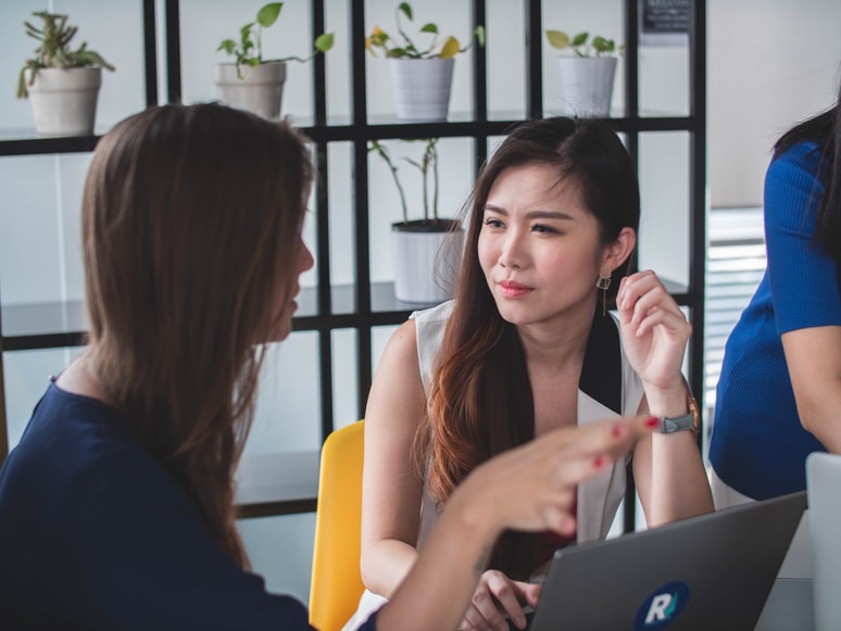 Two women in an office talking to one another 