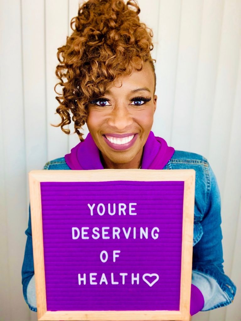 LJ Johnson holding a purple sign reading you’re deserving of health