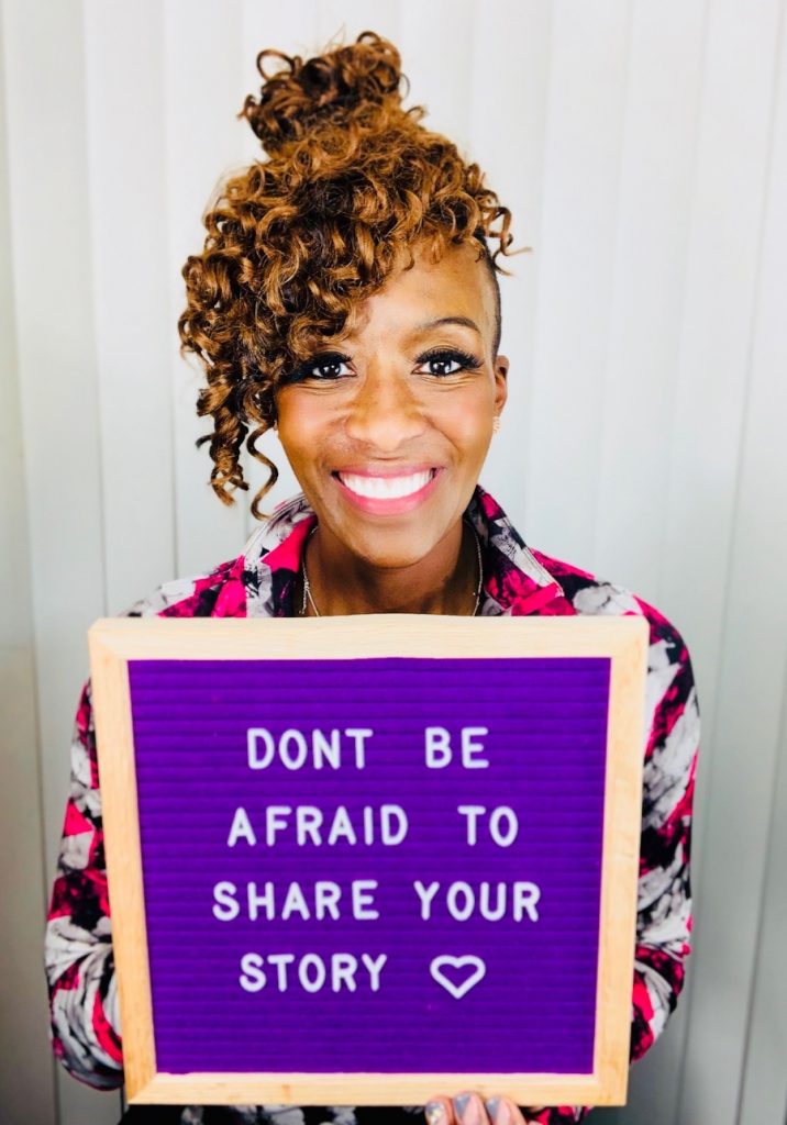 LJ Johnson holding a sign reading don’t be afraid to share your story 