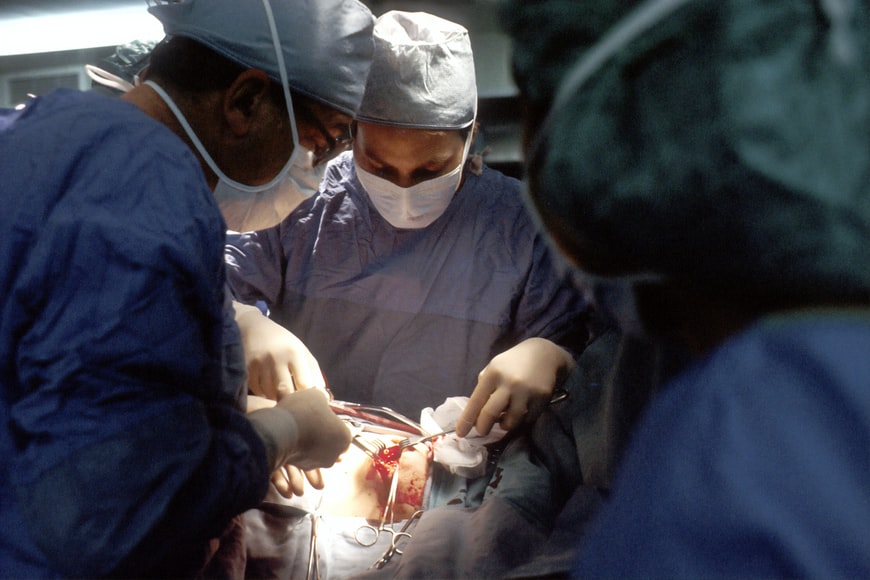 3 doctors wearing personal protective equipment Performing surgery
