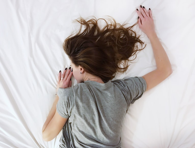 Women with endometriosis laying on a bed 