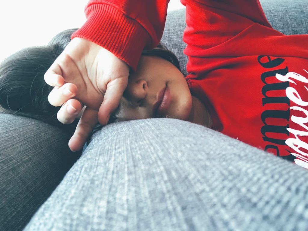 Woman covering face laying on sofa. Fatigue concept. 